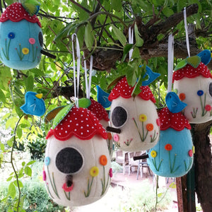 six felt birdhouse pincushions hanging in a tree