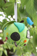 Load image into Gallery viewer, a sewing pattern for a green apple shaped pincushion decorated like a house with embroidered flowers and a bluebird sewing pin
