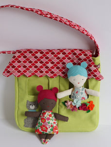 two dolls in a bag that looks like a house