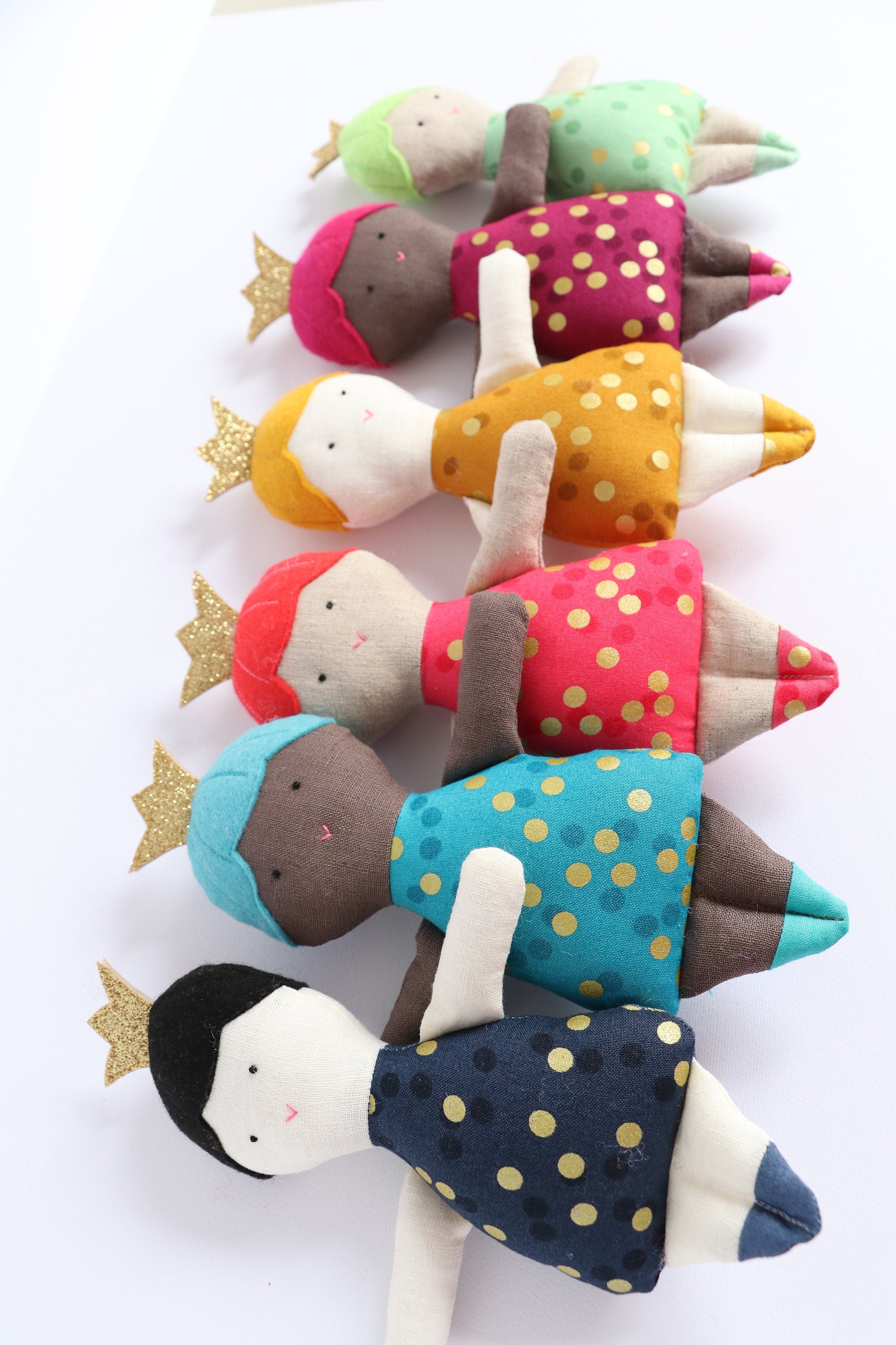 six dolls in different colours wearing crowns