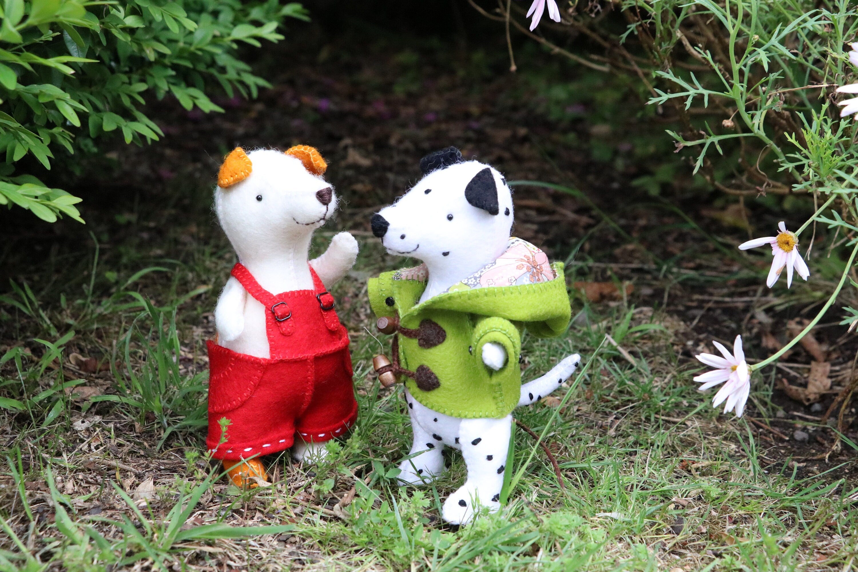 two small felt dog toys standing in a garden